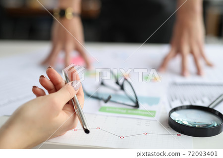 Hands hold pen on table are commercial charts and magnifying glass Hands hold pen on table are commercial charts and magnifying glass 72093401