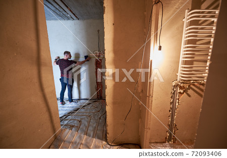 Professional technician measuring the wall in new apartment Professional technician measuring the wall in new apartment 72093406