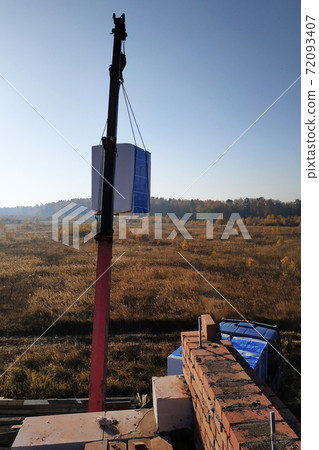 The truck crane transports blocks to the construction site blocks in the air against the sky 72093407