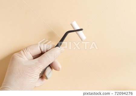 White swab clamped in metal surgical forceps. Accessories for doctors in the surgery room. 72094276