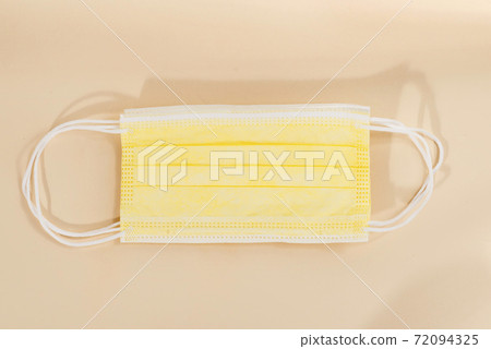Top view of yellow surgical face protection mask isolated on beige color background. 72094325