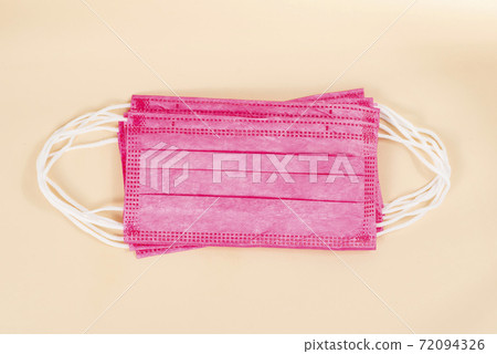 Top view of pink surgical face protection mask isolated on beige color background. Medical mask as part of protection equipment against covid-19 virus outbreak 72094326
