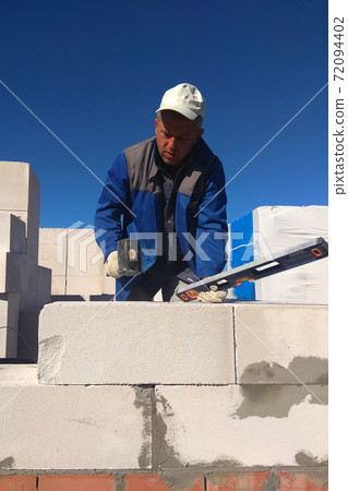 The worker checks the wall of gas blocks by a leveler 72094402