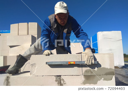 The worker checks the wall of gas blocks by a leveler 72094403