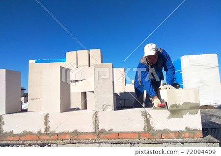 The master monitors the wall with gas blocks using glue and trowel 72094409