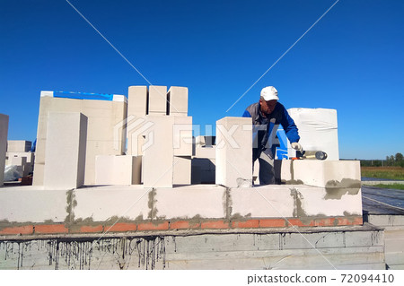 The master monitors the wall with gas blocks using glue and trowel The master monitors the wall with gas blocks using glue and trowel 72094410