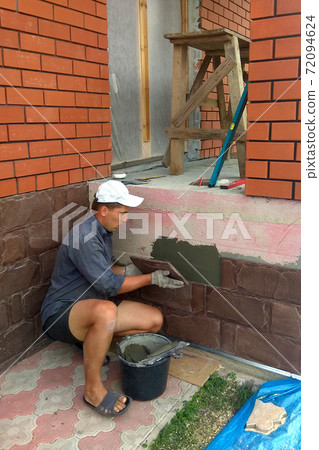 gluing a granite stone on the foundation of the building facing gluing a granite stone on the foundation of the building facing 72094624