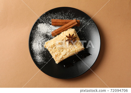 Plate with piece of Napoleon cake with cinnamon on craft background Plate with piece of Napoleon cake with cinnamon on craft background 72094706