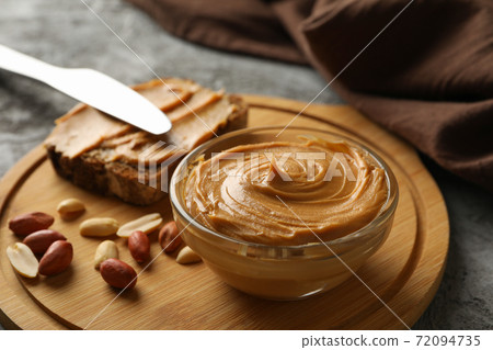 Concept of tasty breakfast with peanut and peanut butter on gray table Concept of tasty breakfast with peanut and peanut butter on gray table 72094735