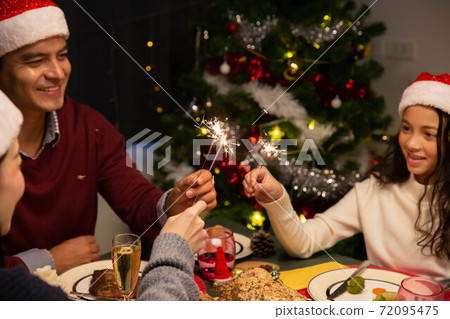 A family celebrate Christmas time together with dinner and sparkling during dinner - focus at sparkler 72095475