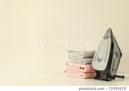 Iron and pile of towels on white background 72095629