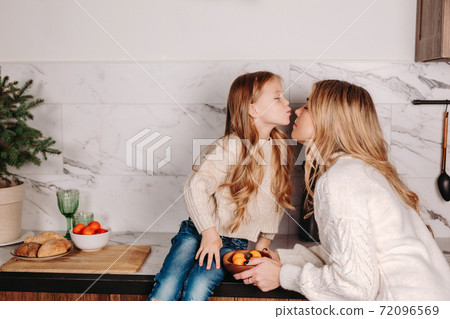 happy mother and little daughter hugging while having breakfast at home in morning 72096569