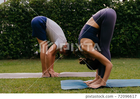 Couple doing yoga in backyard together 72096617