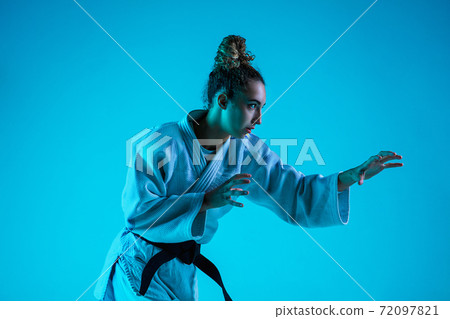 Professional female judoist training isolated on blue studio background in neon light. Healthy lifestyle, sport concept. Professional female judoist training isolated on blue studio background in neon light. Healthy lifestyle, sport concept. 72097821