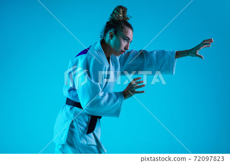 Professional female judoist training isolated on blue studio background in neon light. Healthy lifestyle, sport concept. Professional female judoist training isolated on blue studio background in neon light. Healthy lifestyle, sport concept. 72097823