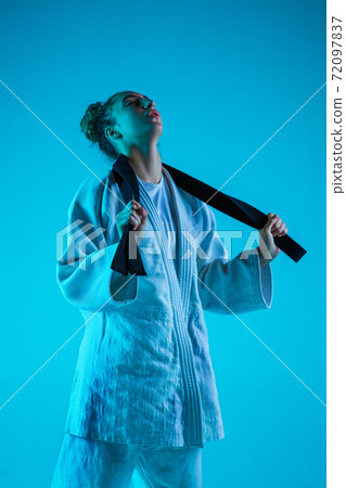 Young girl professional judoist isolated on blue studio background in neon light. Healthy lifestyle, sport concept. Young girl professional judoist isolated on blue studio background in neon light. Healthy lifestyle, sport concept. 72097837