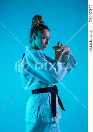 Professional female judoist posing isolated on blue studio background in neon light. Healthy lifestyle, sport concept. Professional female judoist posing isolated on blue studio background in neon light. Healthy lifestyle, sport concept. 72097845
