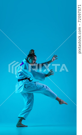 Young girl professional judoist isolated on blue studio background in neon light. Healthy lifestyle, sport concept. Young girl professional judoist isolated on blue studio background in neon light. Healthy lifestyle, sport concept. 72097871