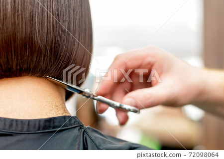 Hairdresser cuts hair tips. 72098064