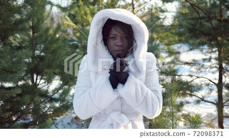 dark-skinned woman trembles with cold and warms hands dark-skinned woman trembles with cold and warms hands 72098371