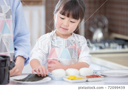 Family girl who wraps seaweed on rice balls Family girl who wraps seaweed on rice balls 72099439