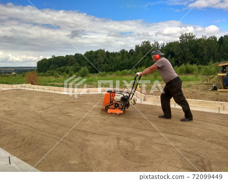 Soil compaction by a worker with a vibroplate Soil compaction by a worker with a vibroplate 72099449