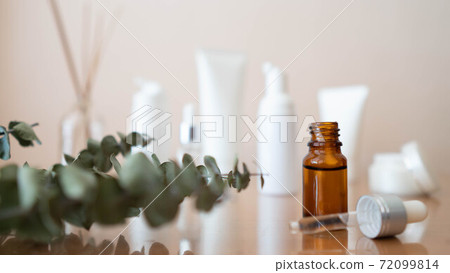 Serum or essential oil with organic herbal extract. Brown glass vial with dropper and skincare bottles on wooden table. Natural cosmetic, spa, beauty product and aromatherapy concept. 72099814