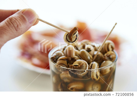 man eating caracolillos, spanish recipe of snails 72100856