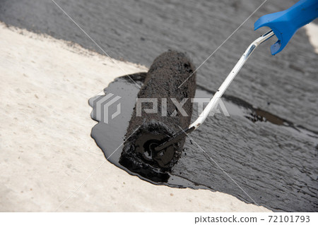 Worker applies bitumen mastic on the foundation Worker applies bitumen mastic on the foundation 72101793