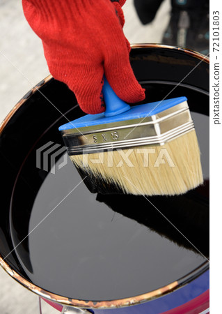 Roofer's hand in red mittens holding a brush 72101803