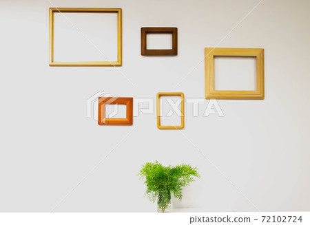 Empty picture frames on white wall and fern leaves in glass on the table Empty picture frames on white wall and fern leaves in glass on the table 72102724