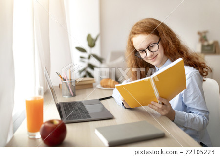 Girl wearing glasses, sitting at desk, doing homework Girl wearing glasses, sitting at desk, doing homework 72105223