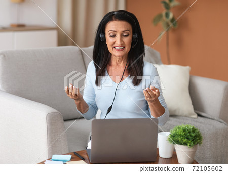 Woman in headset having video call on computer 72105602