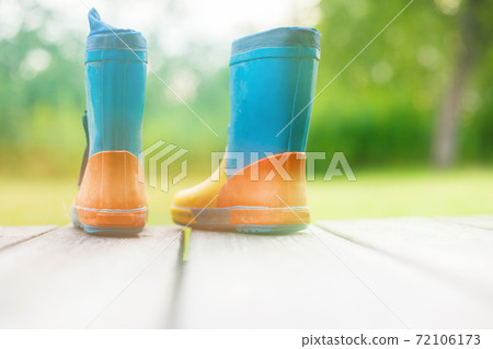 rubber boots on a wooden background. children's rubber boots on a background of green grass 72106173
