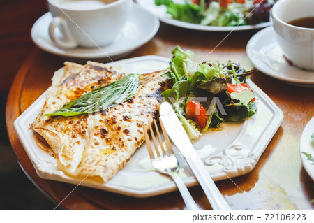 Fresh baked french savory crepes served with green Fresh baked french savory crepes served with green 72106223