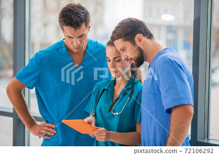 Group of doctors watching something on tablet and looking serious 72106292