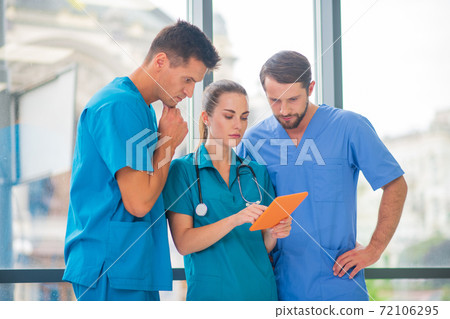 Group of doctors watching something on tablet and looking serious 72106295