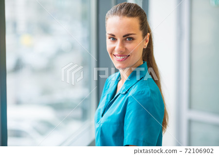 Pretty young female doctor in blue uniform smiling nicely 72106902