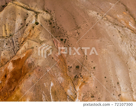 Aerial shot of the textured yellow nad red mountains resembling the surface of Mars 72107300
