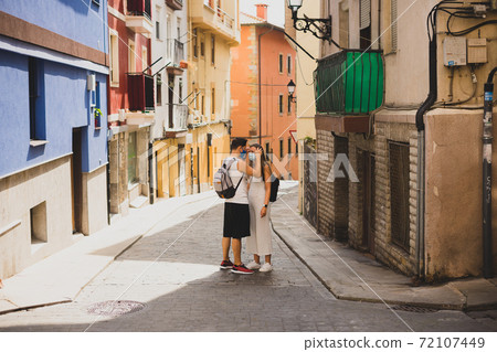 Couple with face masks on a pintoresque small village 72107449