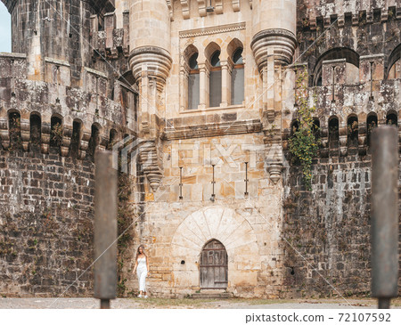 Young woman in front of a medieval castle Young woman in front of a medieval castle 72107592