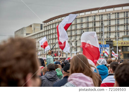 A crowd of people with a large flag goes during a rally A crowd of people with a large flag goes during a rally 72109503