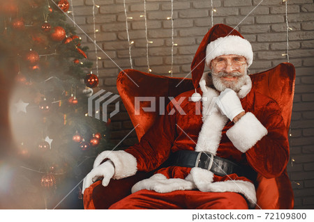 Man in santa claus costume sitting on a chair Man in santa claus costume sitting on a chair 72109800