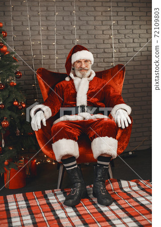 Man in santa claus costume sitting on a chair Man in santa claus costume sitting on a chair 72109803