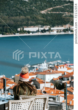 The girl in santa's hat sits in the background of the city and roofs The girl in santa's hat sits in the background of the city and roofs 72112854