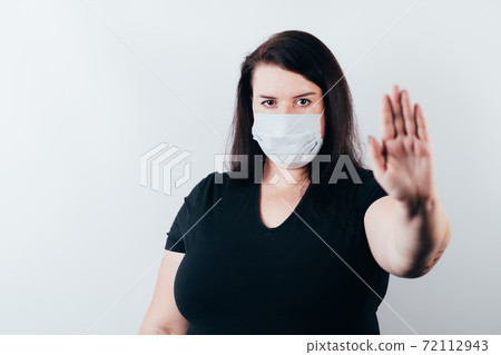 Woman in medical mask pointing thumb on copy space Woman in medical mask pointing thumb on copy space 72112943