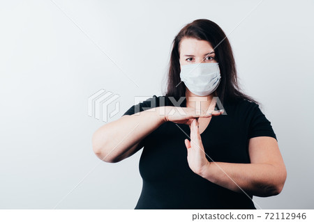 Woman in medical mask showing T sign with hands 72112946