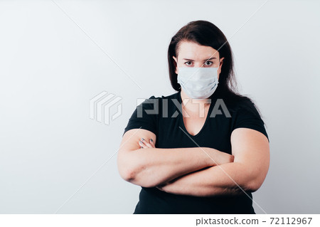 Woman in medical mask folding arms on chest 72112967