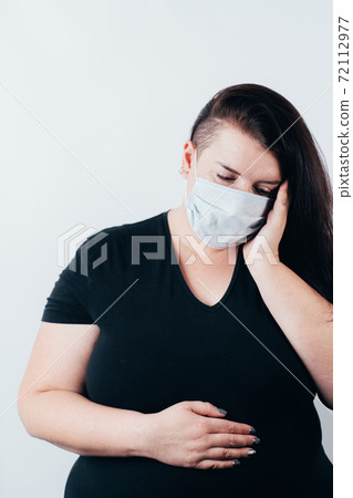 Woman in mask suffering from headache and pain 72112977
