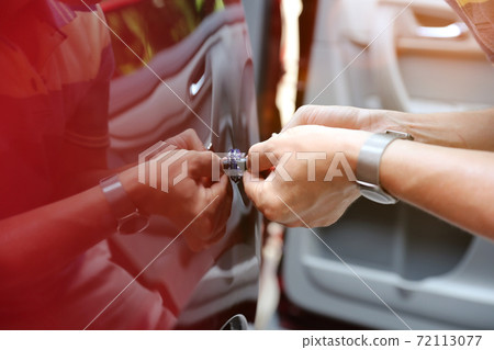 Man fixing car dent by himself 72113077